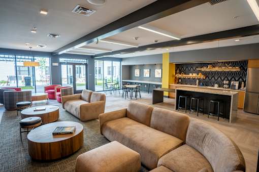 A modern lounge area with a variety of seating options and a bar area at The Hive Apartments, Allentown 18101