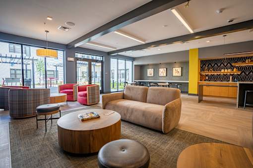 A modern living room with a wooden coffee table and a grey ottoman at The Hive Apartments, Allentown