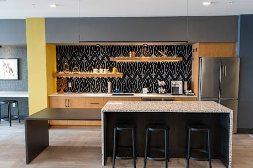 A modern kitchen with a bar area and stools at The Hive Apartments, Pennsylvania