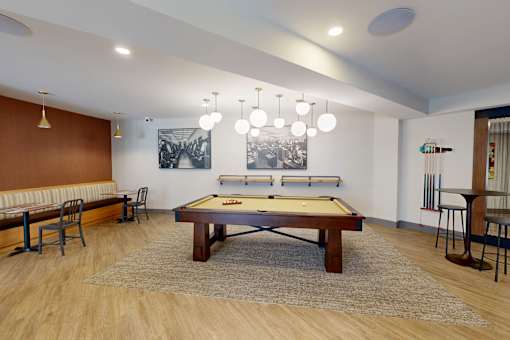 A pool table is in the middle of a room with a bench and chairs at The Standard Apartments, Pennsylvania, 18101