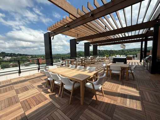A wooden deck with tables and chairs and a pergola.