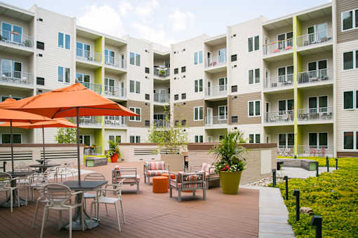 an outdoor patio at an apartment complex with tables and umbrellas