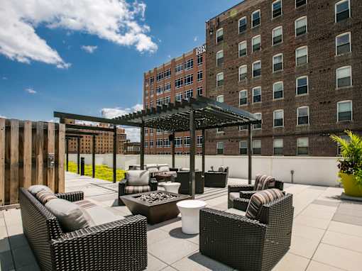 a rooftop patio with wicker furniture and a wooden fence