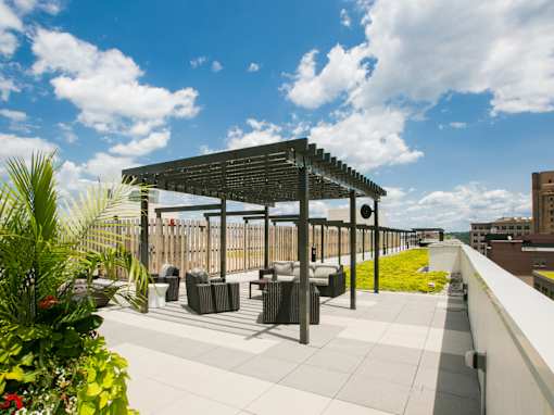a roof terrace with tables and chairs and a pergola on a rooftop