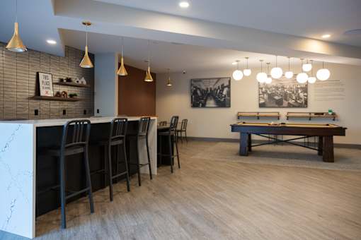 A room with a pool table and bar area.