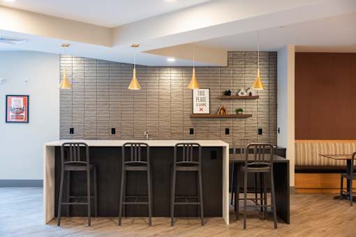 A bar area with a row of stools in front of it.