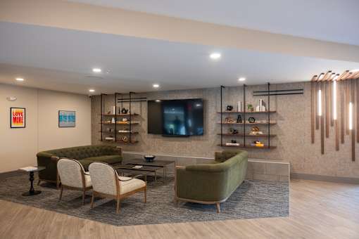 A living room with a green couch, a chair, a coffee table, and a television.