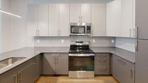 A modern kitchen with stainless steel appliances and white cabinets at The Standard Apartments, Allentown, PA