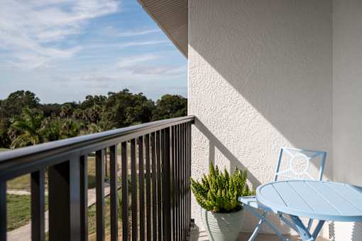 A balcony with a blue chair and table.at The Teale Golden Gate in Naples, FL, 34116
