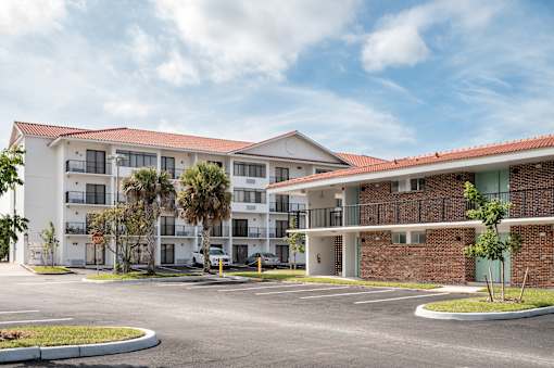 A large apartment complex with a parking lot in front.at The Teale Golden Gate in Naples, FL, 34116