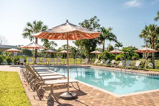A pool surrounded by lawn chairs and umbrellas.