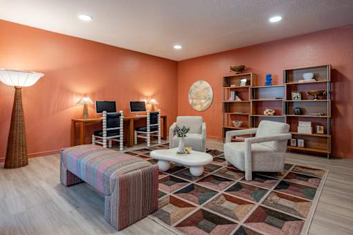 A living room with a striped ottoman, a white table, and a rug with a geometric pattern.