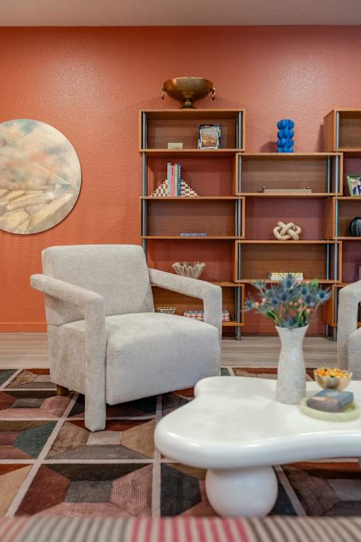 A living room with a chair, a table, and a shelf with various objects.