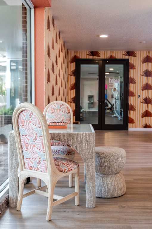 A chair with a patterned cushion is placed in front of a glass table.