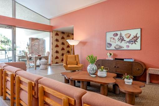 A living room with a pink wall and wooden furniture.