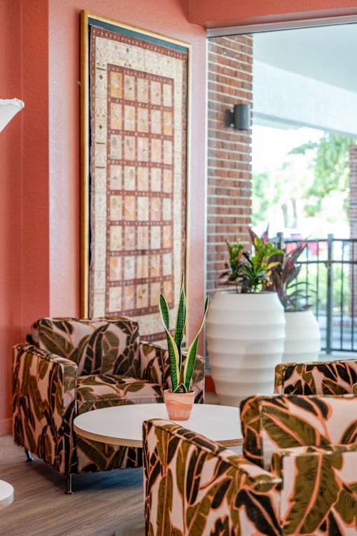 A living room with a couch, chairs, and a table with a plant on it.