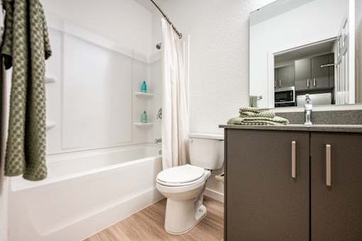 A white toilet sits in a bathroom next to a bathtub.