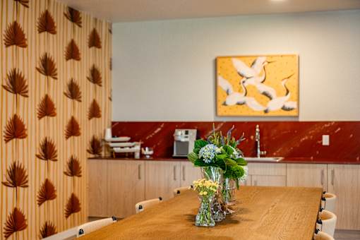 A dining room with a wooden table and a painting on the wall.