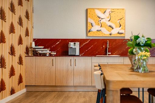 A kitchen with a wooden table and a painting of birds on the wall.