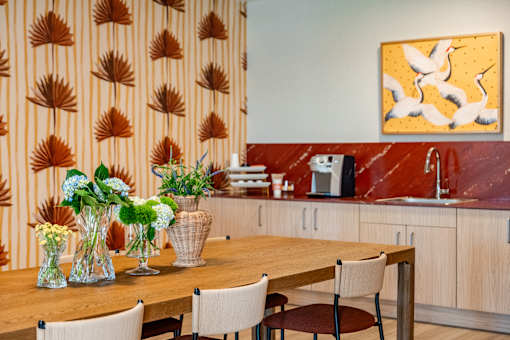 A kitchen with a wooden table and chairs, a sink, and a painting on the wall.