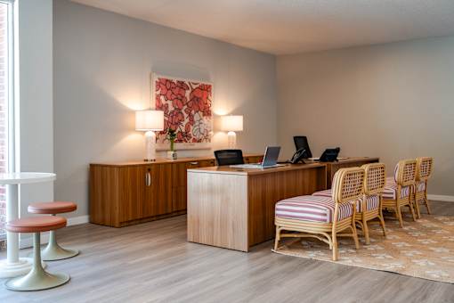 A room with a desk, chairs, and a painting on the wall.