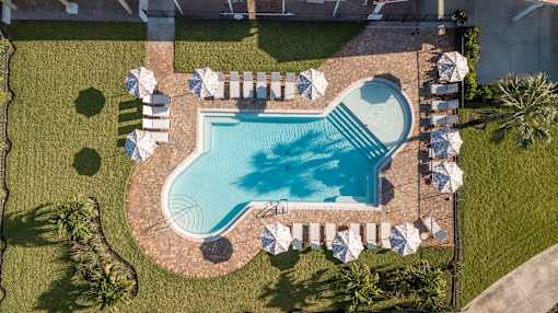 An aerial view of a swimming pool surrounded by lawn chairs and umbrellas.