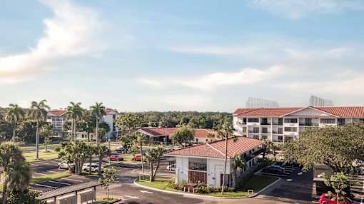 A view of a residential area with apartment buildings and cars parked in the driveways.