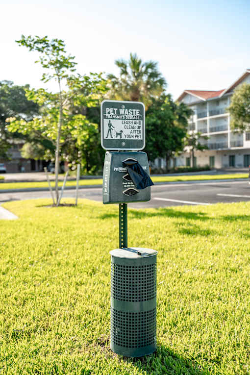 A sign on a pole in the grass that says "Pet Waste".