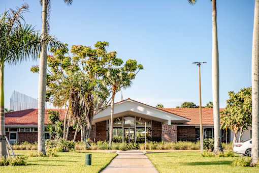 A building with a red roof is surrounded by palm trees.