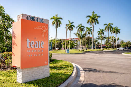 A sign for The Teale Golden Gate Apartments stands in front of a row of palm trees.