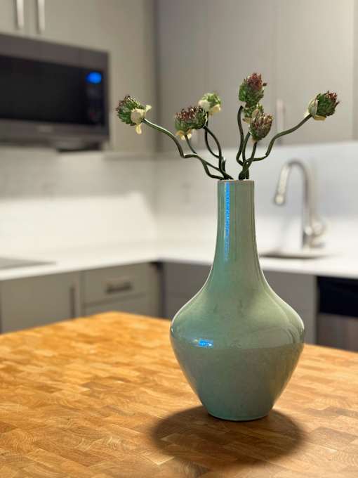 A green vase with flowers on a wooden table in a kitchen at The Teale Siesta Lago in Kissimmee, FL, 34746