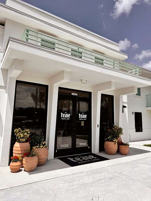 The front of a white building with a black door and windows.