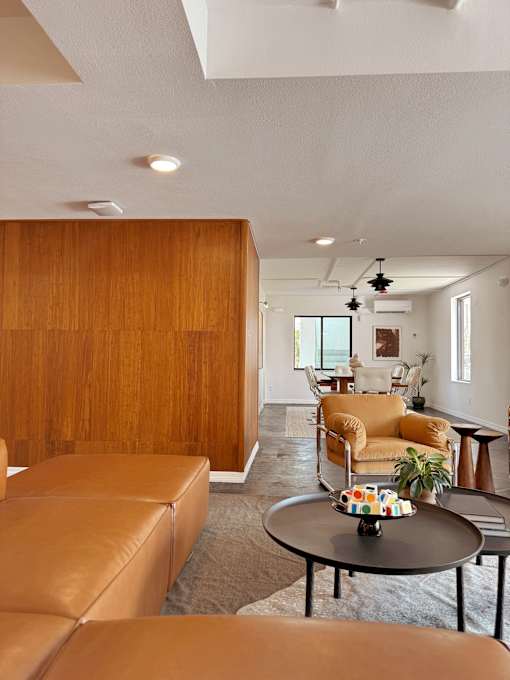 A living room with a brown leather couch and a wooden wall.