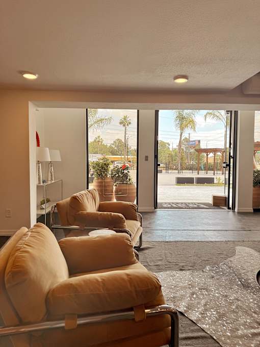 A living room with a row of couches and a view of the outdoors through the sliding glass doors.