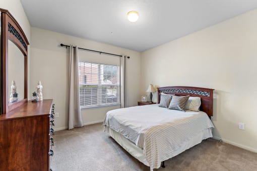 a bedroom with a bed and a dresser and a window