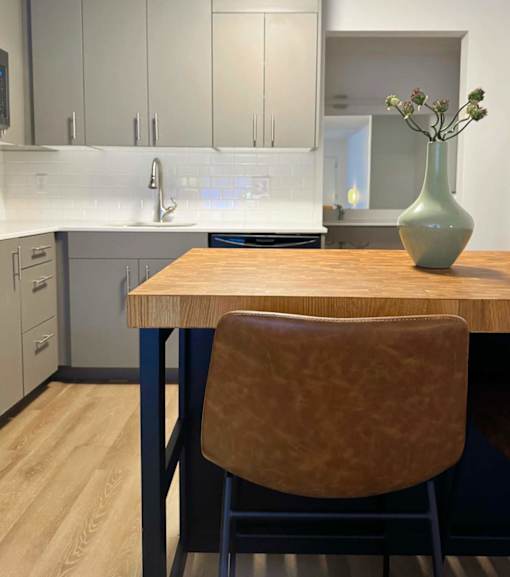 A kitchen with a wooden table and a brown chair. at The Teale Golden Gate in Naples, FL, 34116