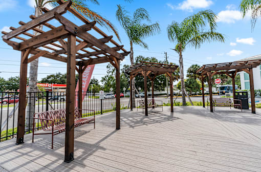A wooden pergola with benches is situated in a park at The Teale Siesta Lago in Kissimmee, FL, 34746