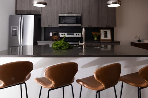 a kitchen with a counter and chairs and a refrigerator  at The Lady, Columbia, 29201