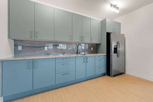 A kitchen with blue cabinets and a black refrigerator.