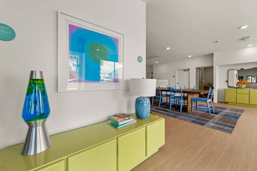 A modern living room with a yellow sideboard and a blue lamp.
