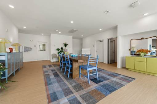 A dining room with a blue rug and chairs.