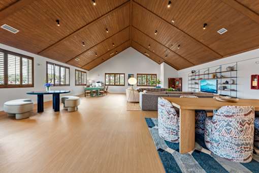 A room with a wooden floor and ceiling, furnished with a table and chairs.