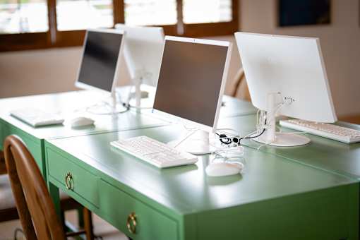 Three computer monitors are on a green desk.
