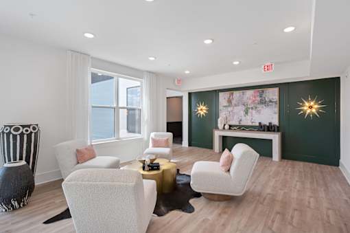 A living room with a white sofa, a white chair, a white coffee table, a black and white sculpture, a green wall, and a white fireplace.