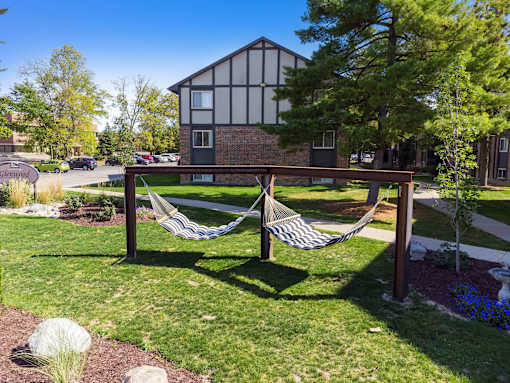 A hammock is strung between two wooden posts in a grassy area.