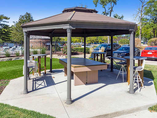 A gazebo with a table and chairs is set up in a park.