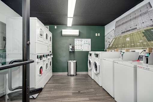 A laundromat with a green wall and a picture of a football stadium.