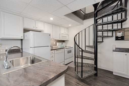 A kitchen with a spiral staircase in the middle.