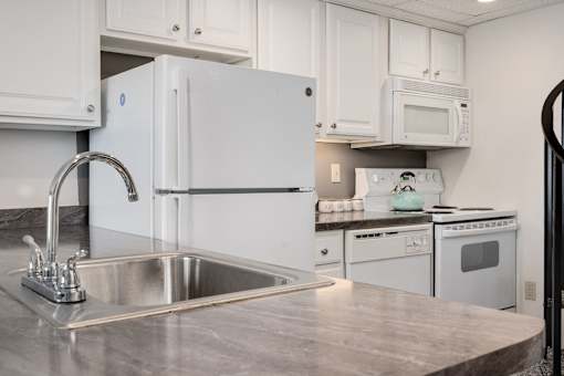 A kitchen with a white fridge and a stainless steel sink.