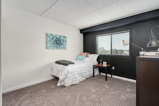A bedroom with a bed, nightstand, and a window.
